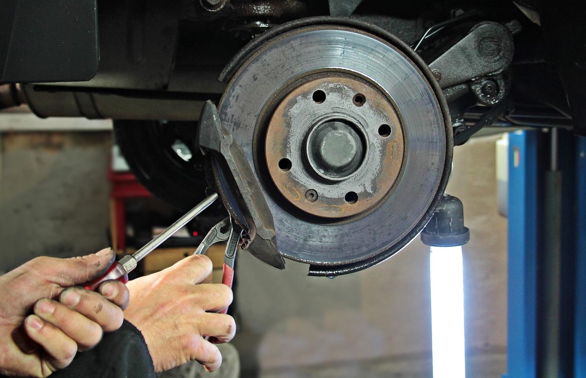 Emergency brake repair — mechanic working on worn brake rotor and pads in Los Angeles